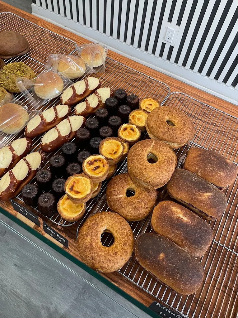 Cooling rack with canelés, cheese tarts, pretzel sticks, and red bean bread