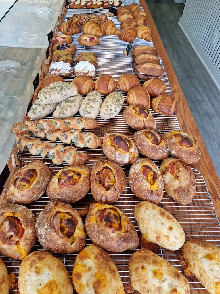 Cooling racks of croissants, danishes, and loaves at Bricolage Bakery